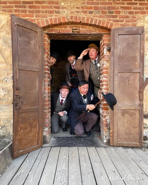 Living history performers in period costume gathered in a heavy brick doorway in Columbia